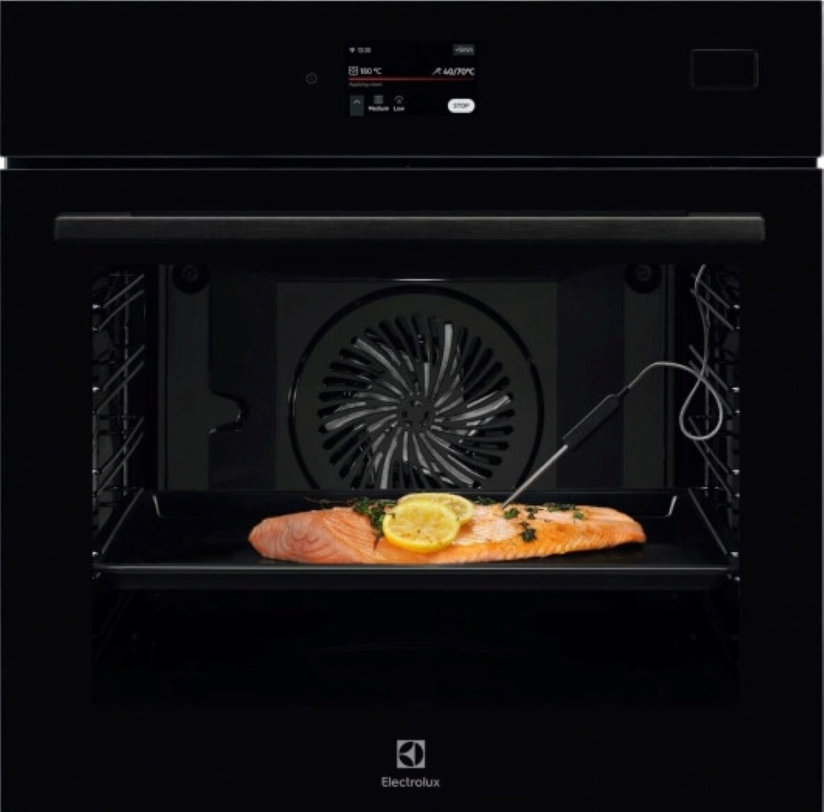 Otwarty czarny piekarnik z łososiem, plasterkami cytryny i ziołami na tacy. Włożono sondę temperatury.