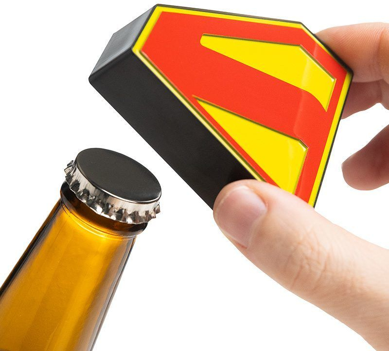 Egy kéz egy Superman-palacknyitót tart egy sörösüveg mellett. A nyitón egy piros és sárga logó látható.
