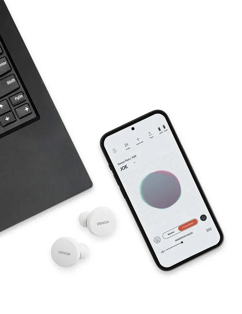 Białe słuchawki Denon, smartfon z aplikacją i klawiatura laptopa na białej powierzchni. Aplikacja pokazuje gradientowe koło.