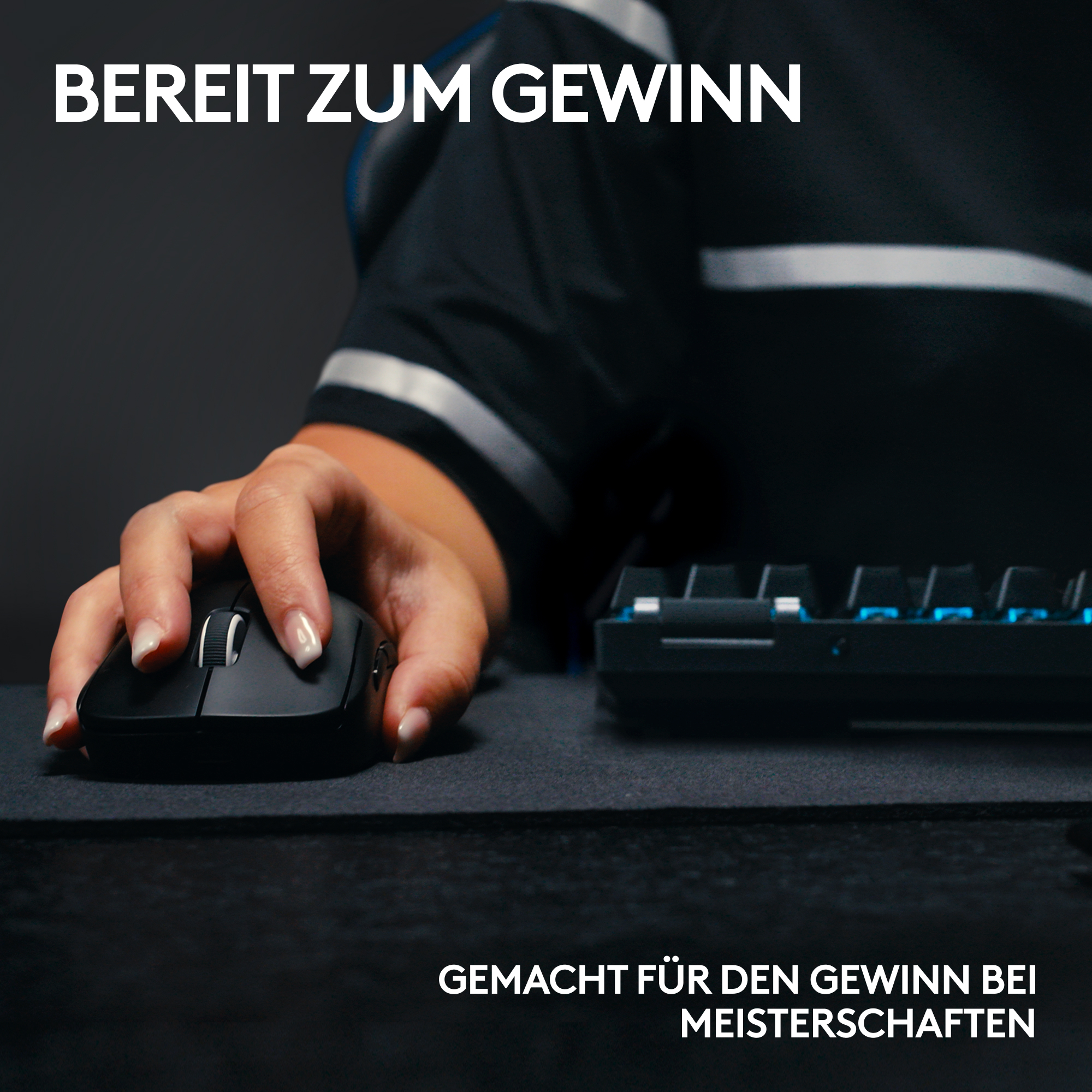 Eine Hand hält eine schwarze Maus auf einer Matte, Tastatur im Hintergrund. Text: BEREIT ZUM GEWINN, GEMACHT FÜR MEISTERSCHAFTEN.