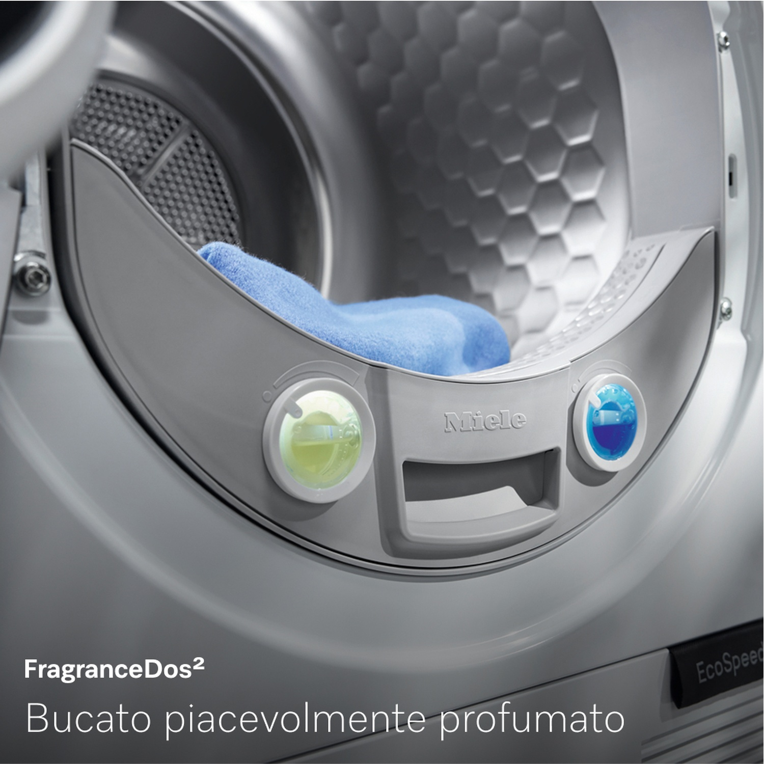Primo piano di un cestello della lavatrice con un asciugamano blu all'interno. Il marchio Miele è visibile e ci sono due dispenser di fragranze.