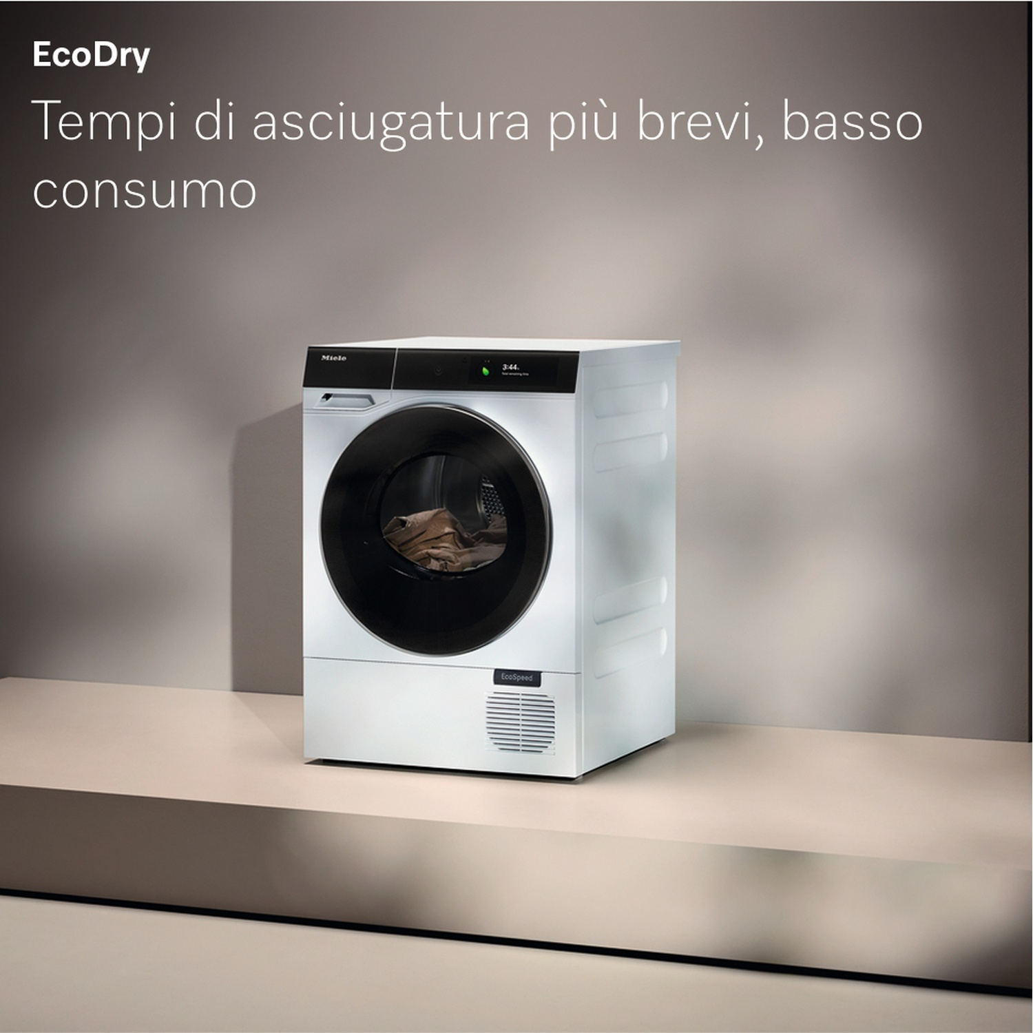 Un'asciugatrice bianca con porta nera su superficie chiara. Testo: 'EcoDry' e 'Tempi di asciugatura più brevi, basso consumo'.