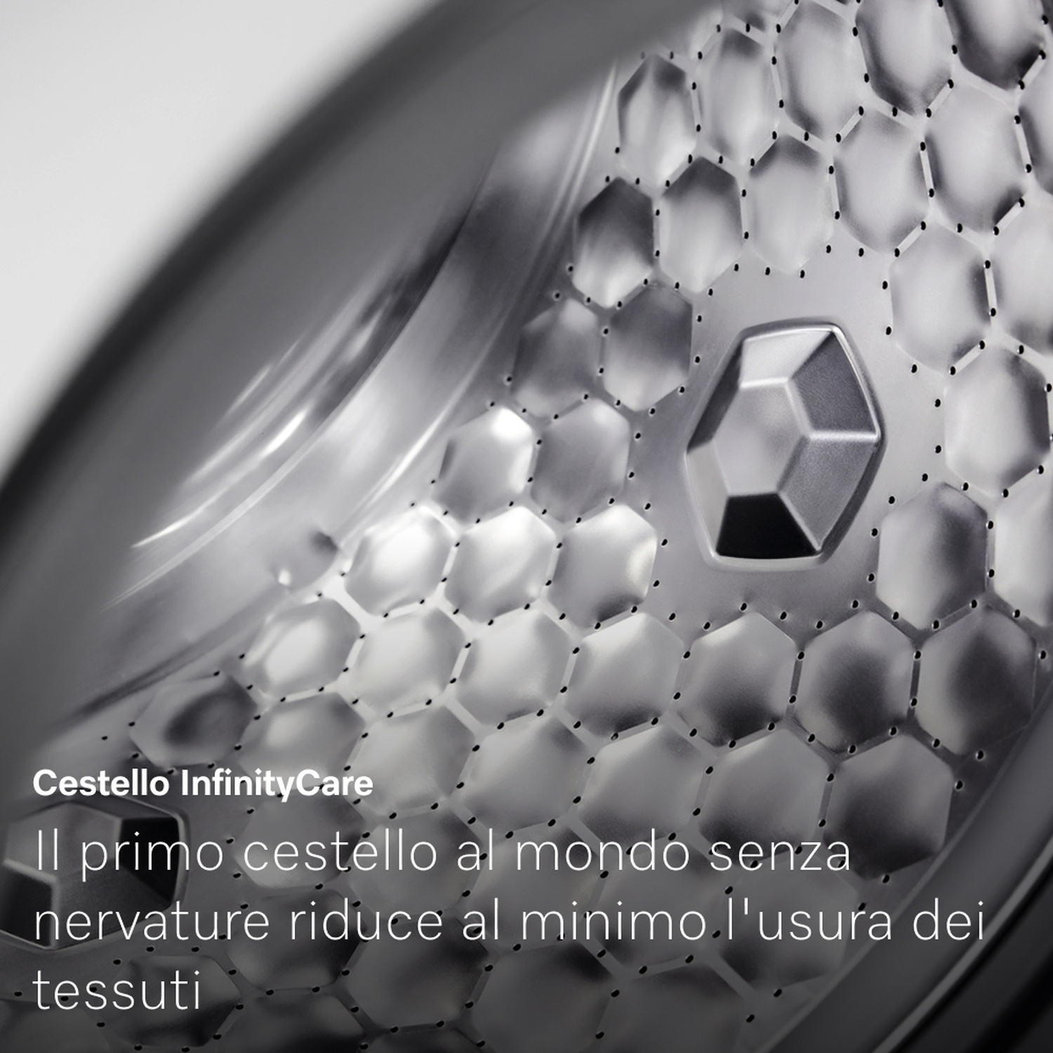 Interno del cestello di una lavatrice. Il cestello è metallico, con un motivo a nido d'ape. Testo in italiano: Cestello InfinityCare.