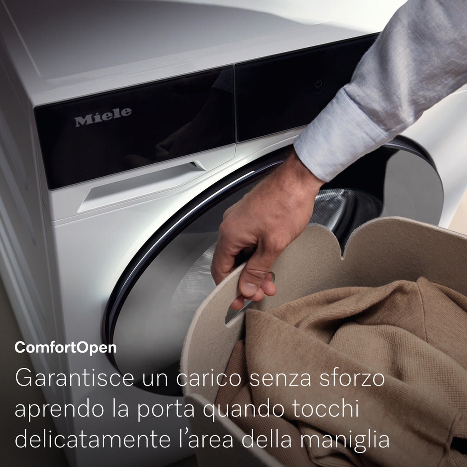 Una persona apre lo sportello di una lavatrice Miele, tenendo un cesto beige con vestiti piegati. La macchina è bianca e il testo "Miele" è visibile.