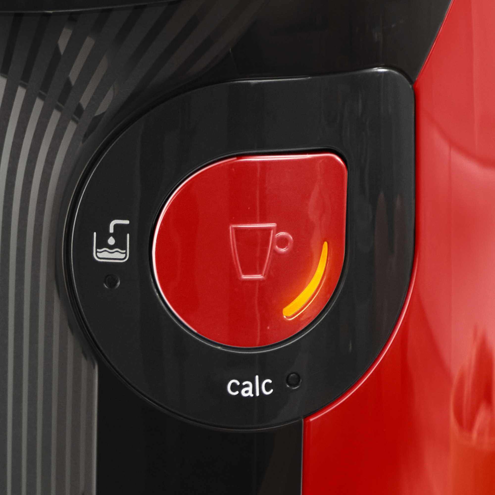 Primer plano del botón de una cafetera. Botón rojo con un símbolo de taza, enmarcado en negro, con 'calc' escrito debajo.
