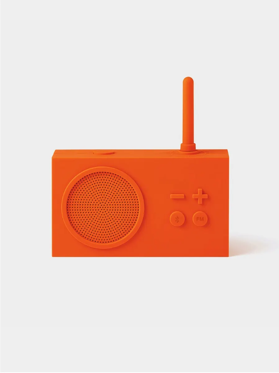 Ein orangefarbenes Radio mit Lautsprecher, Antenne und Bedienelementen. Der Hintergrund ist schlicht weiß.