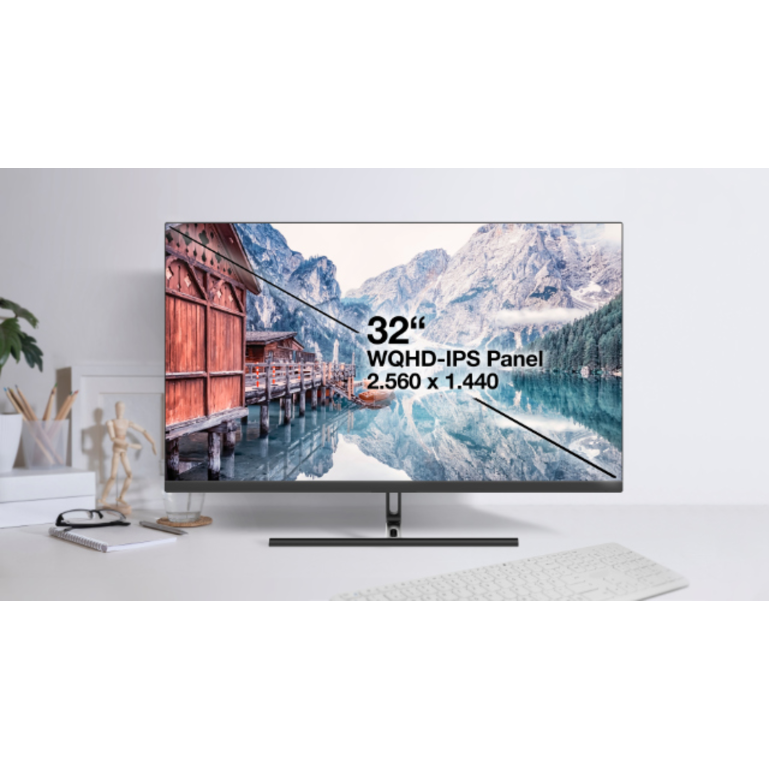 A 32-inch monitor displays a mountain lake scene. A keyboard and desk items are in the foreground.