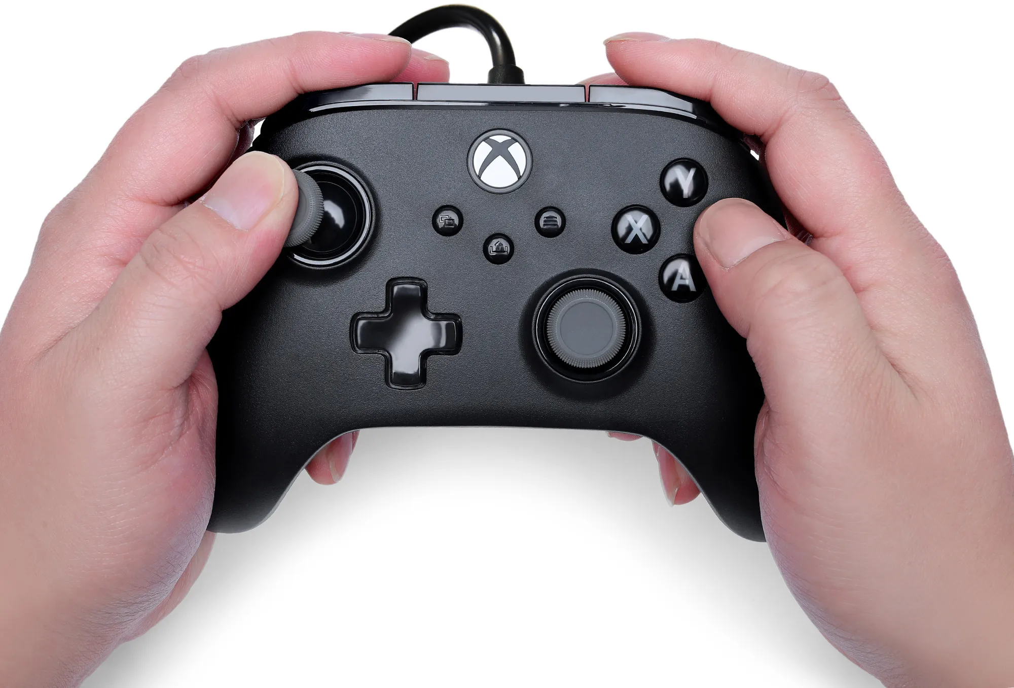 Hände halten einen schwarzen Xbox-Controller. Knöpfe und Joysticks sind sichtbar. Weißer Hintergrund.