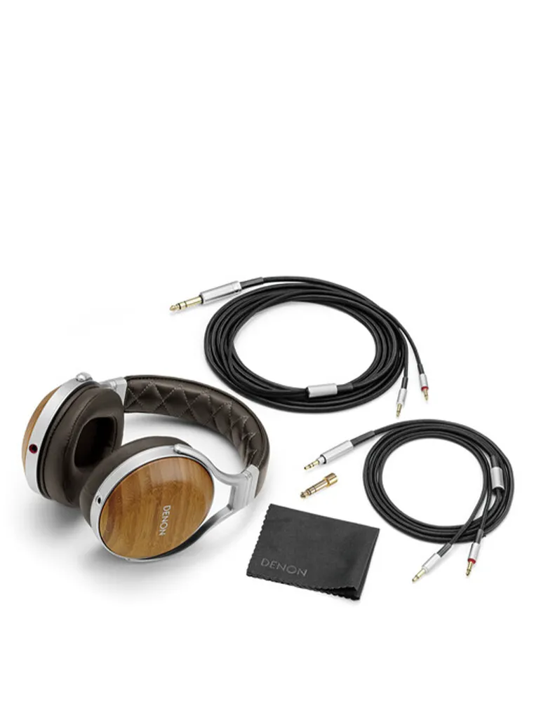 Słuchawki z drewnianymi nausznikami, kablami i ściereczką do czyszczenia. Czarne kable są zwinięte. Słuchawki są na białym tle.