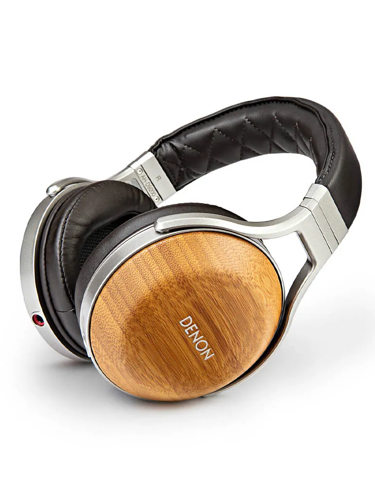 Słuchawki nauszne. Drewniane nauszniki z napisem 'DENON'. Czarny skórzany pałąk i nauszniki. Srebrna metalowa rama. Białe tło.