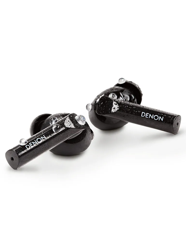 Dwa czarne słuchawki douszne Denon z kroplami wody. Logo jest widoczne. Tło jest białe.