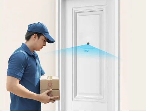 Dostawca w niebieskim trzyma paczki blisko białych drzwi. Niebieski łuk widzenia pokazuje 146 stopni.