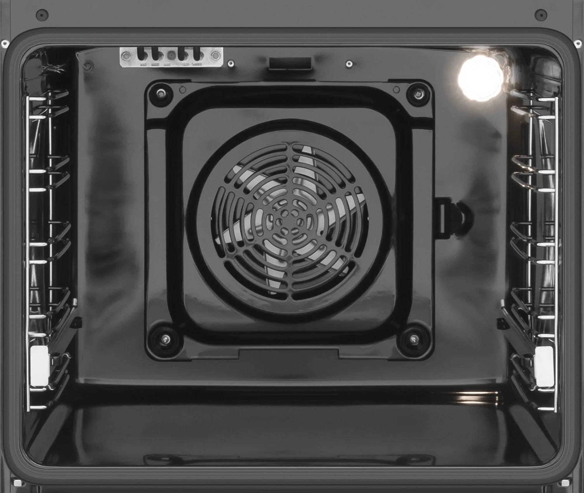 Wnętrze piekarnika. Wentylator jest na środku. Światło piekarnika jest po prawej stronie. Widoczne ruszty.