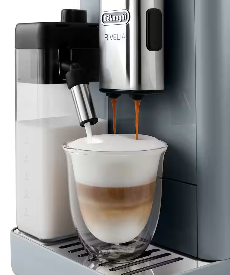 Ekspres do kawy dozuje kawę i mleko do szklanki. Szklanka zawiera warstwy kawy, mleka i pianki.