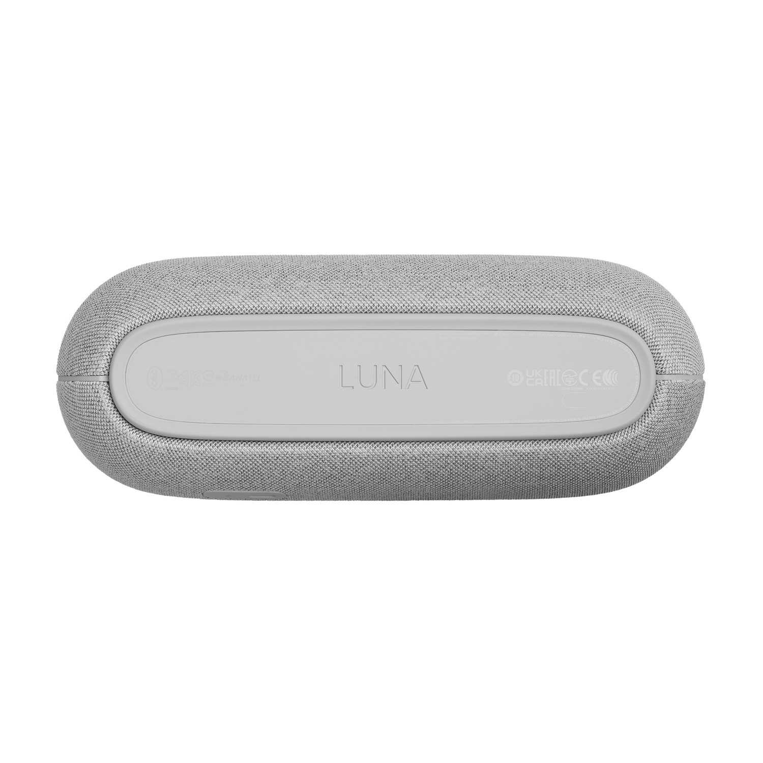 Un altavoz ovalado gris, con la etiqueta 'LUNA', descansa sobre una superficie gris. Detalles incluyen logotipos y texto, la textura es visible.