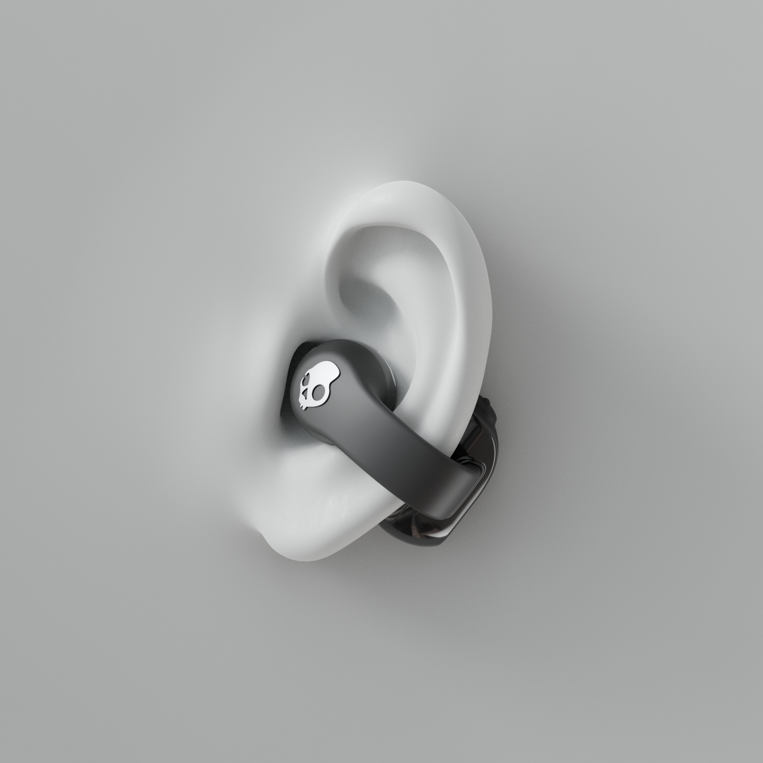 Un écouteur noir avec un logo de crâne est inséré dans une oreille blanche. L'oreille est sur un fond gris.