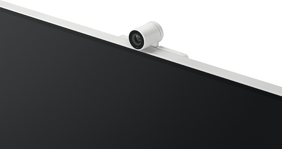 Egy fehér webkamera egy fekete képernyő tetejére van szerelve. A képernyőt fehér keret szegélyezi. Fehér háttér.