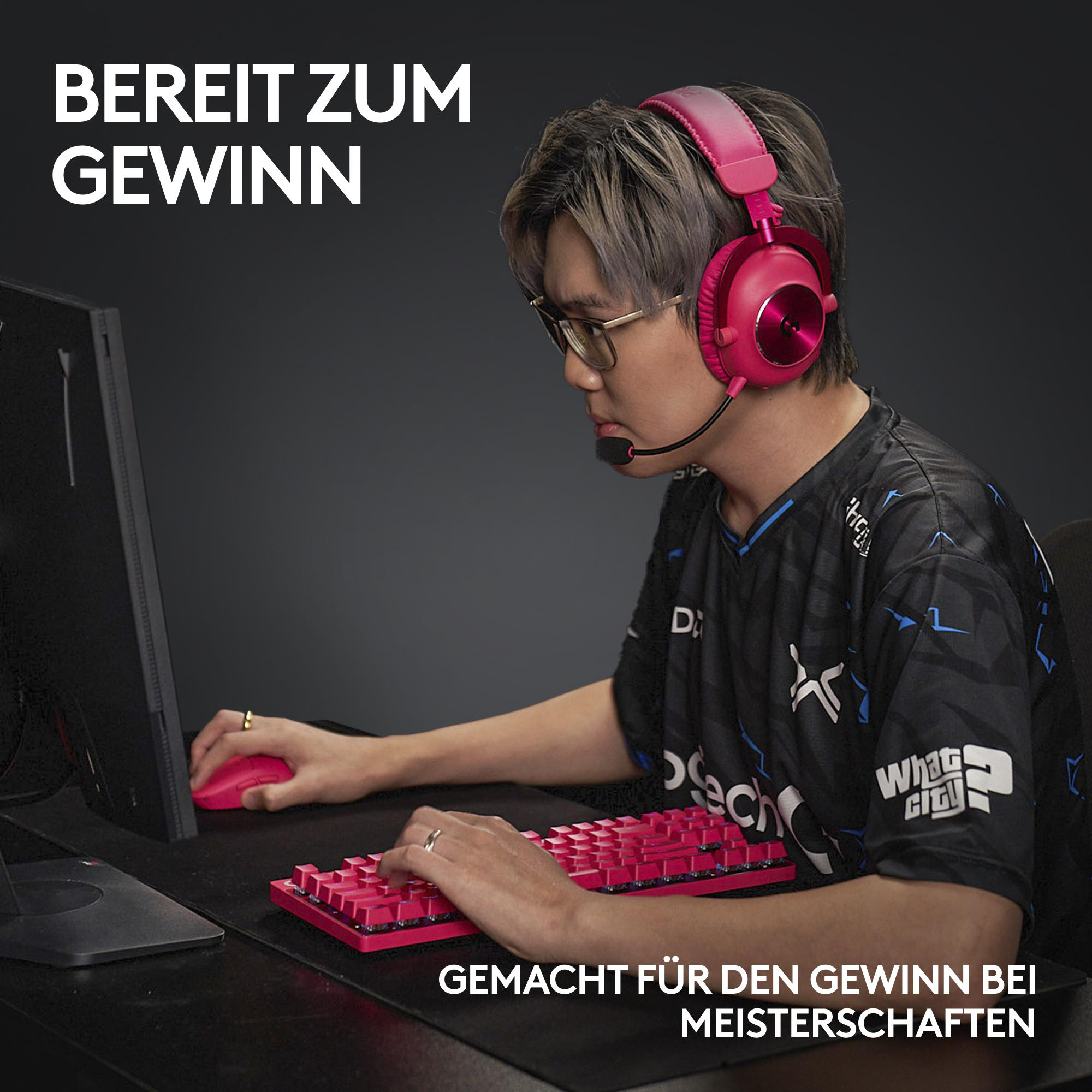 Eine Person mit pinkfarbenen Kopfhörern, die eine pinkfarbene Tastatur und Maus benutzt. Die Person sitzt vor einem Computer.
