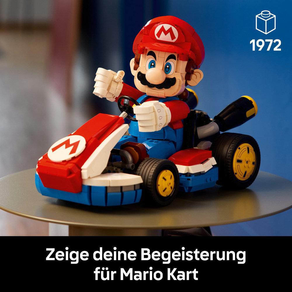 Eine Lego-Mario-Figur in einem roten Kart mit blauen Akzenten. Die Figur trägt eine rote Kappe und blaue Latzhose, auf einem Tisch.