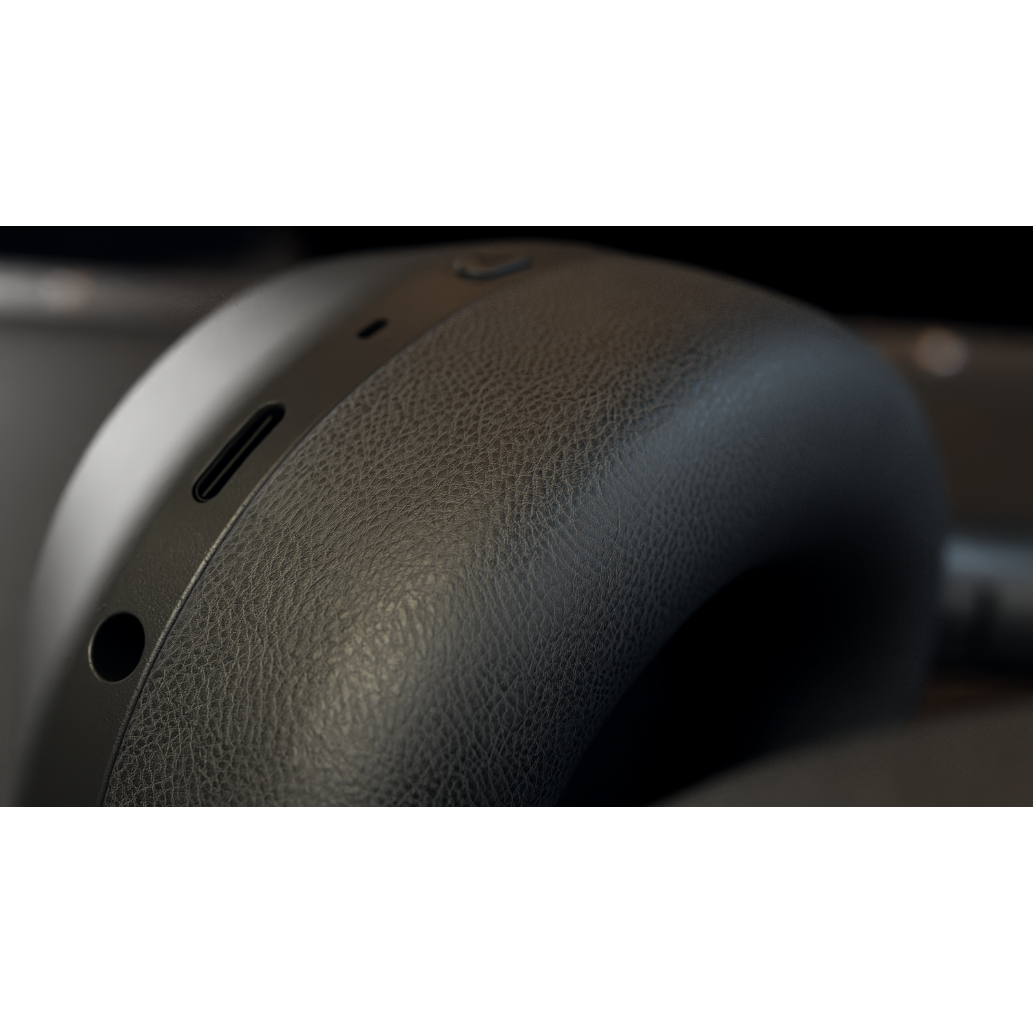 Close-up of black over-ear headphones. Texture of the ear cup is visible, with a charging port and button details. Dark background.