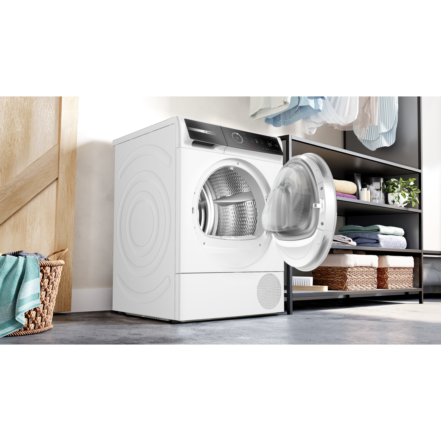 A white dryer with an open door. A laundry basket with a towel is on the left. Shelves with towels and baskets are on the right.