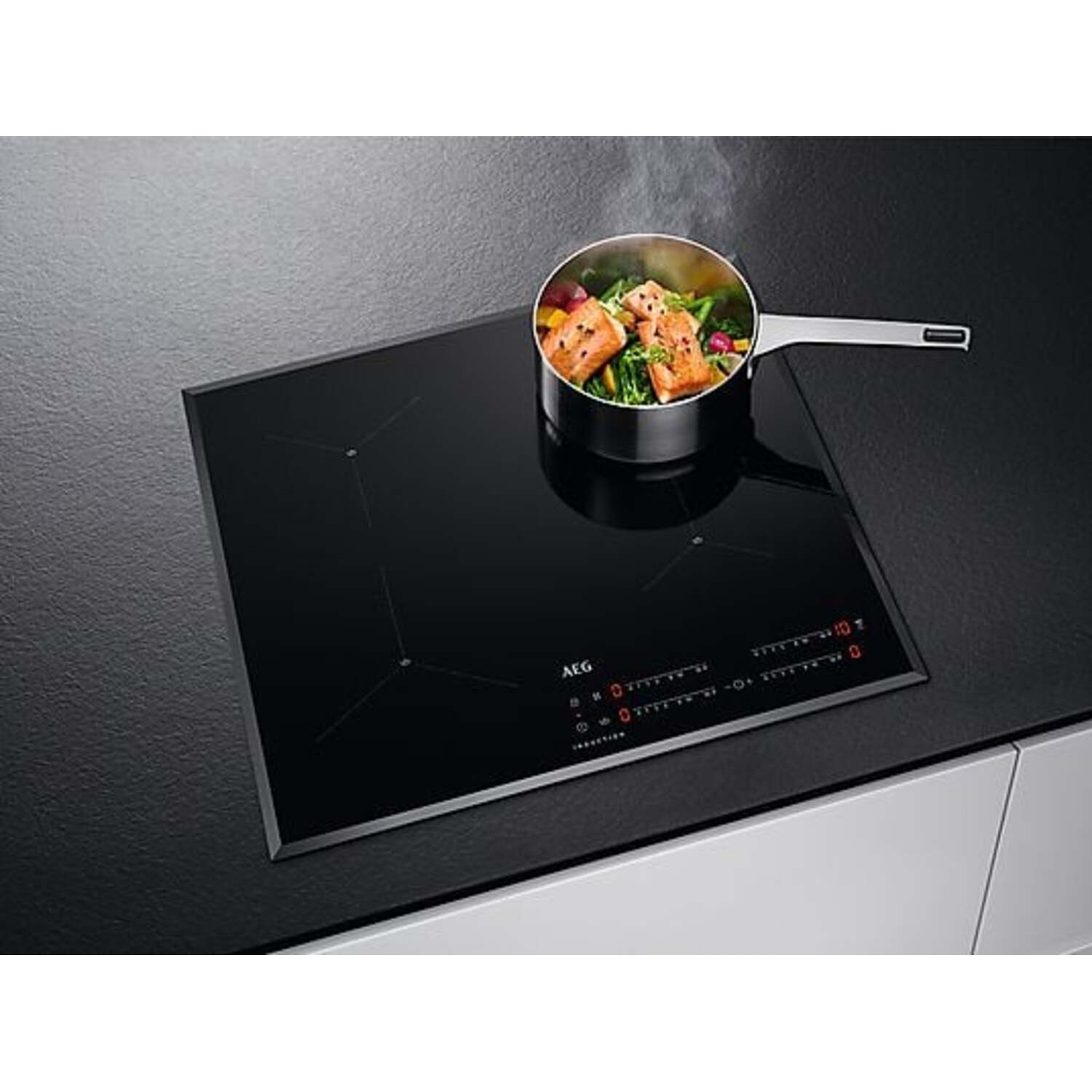 A black induction hob with a saucepan. The pan contains food. Steam rises from the pan.