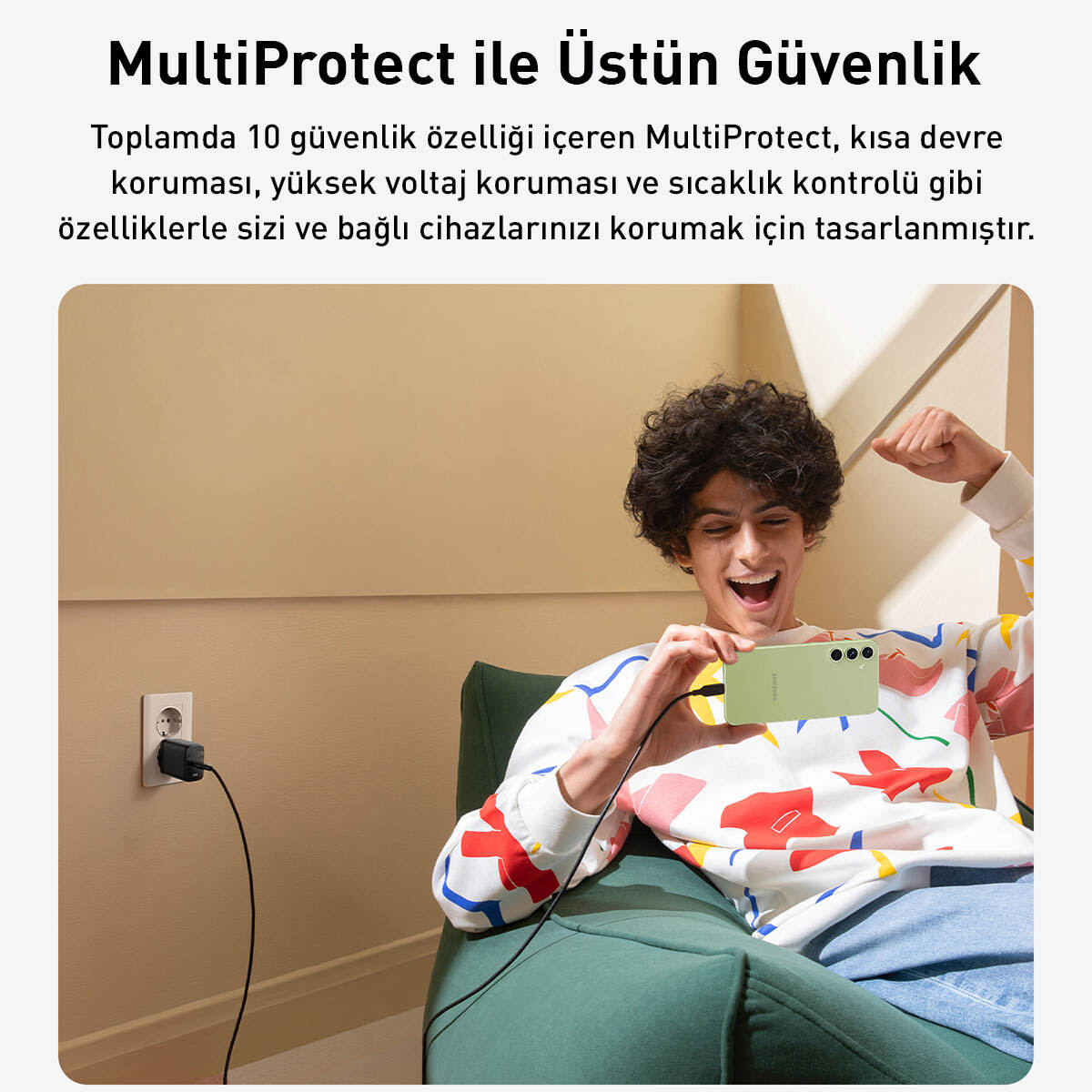 Bir kişi yeşil bir telefon tutuyor, gülümsüyor. Bir şarj cihazı ile bir duvar prizi var. Arka plan bej.