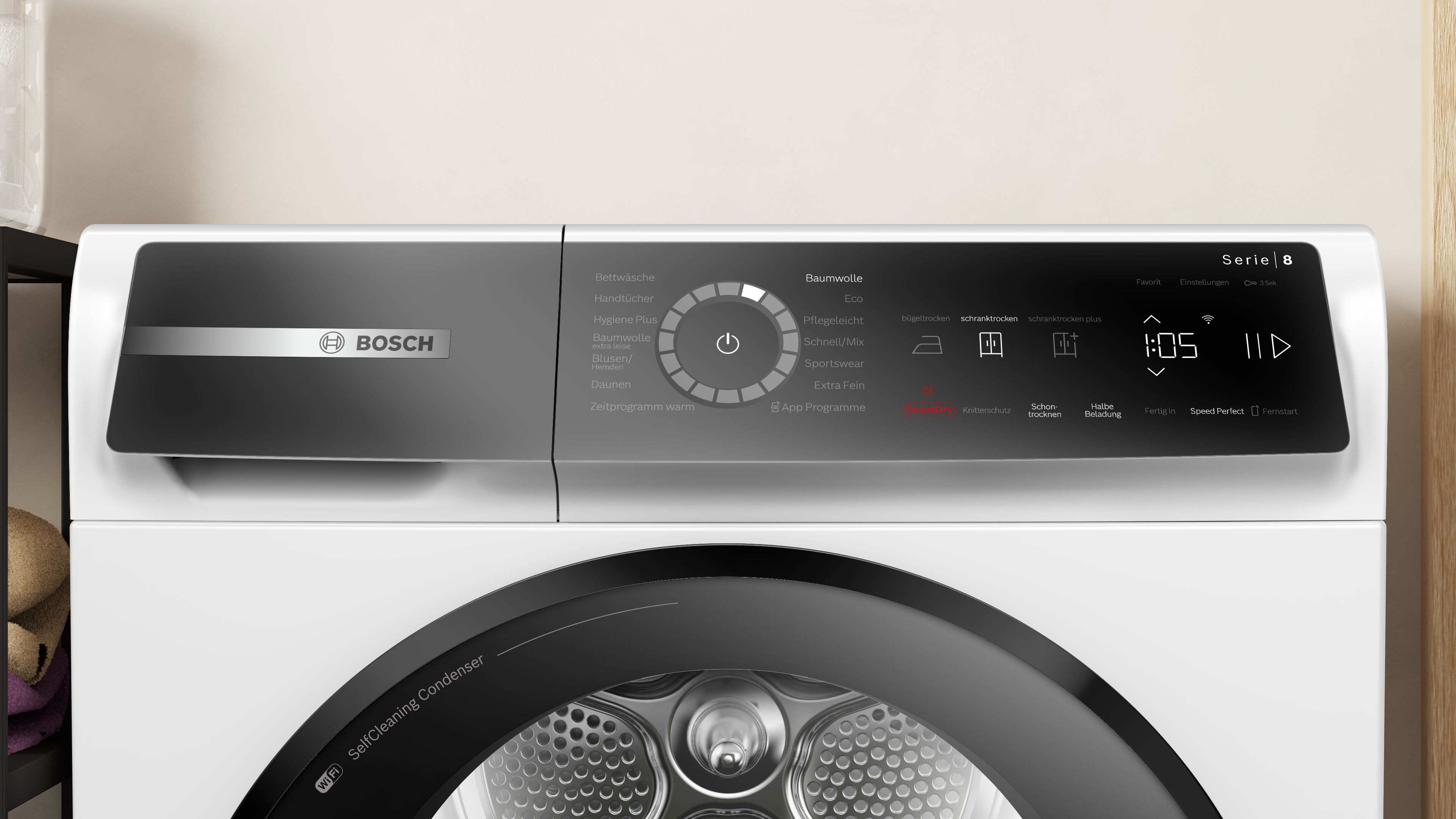 Ein weißer Bosch-Trockner mit schwarzem Bedienfeld. Es hat verschiedene Einstellungen und eine Digitalanzeige. Die Tür ist schwarz.