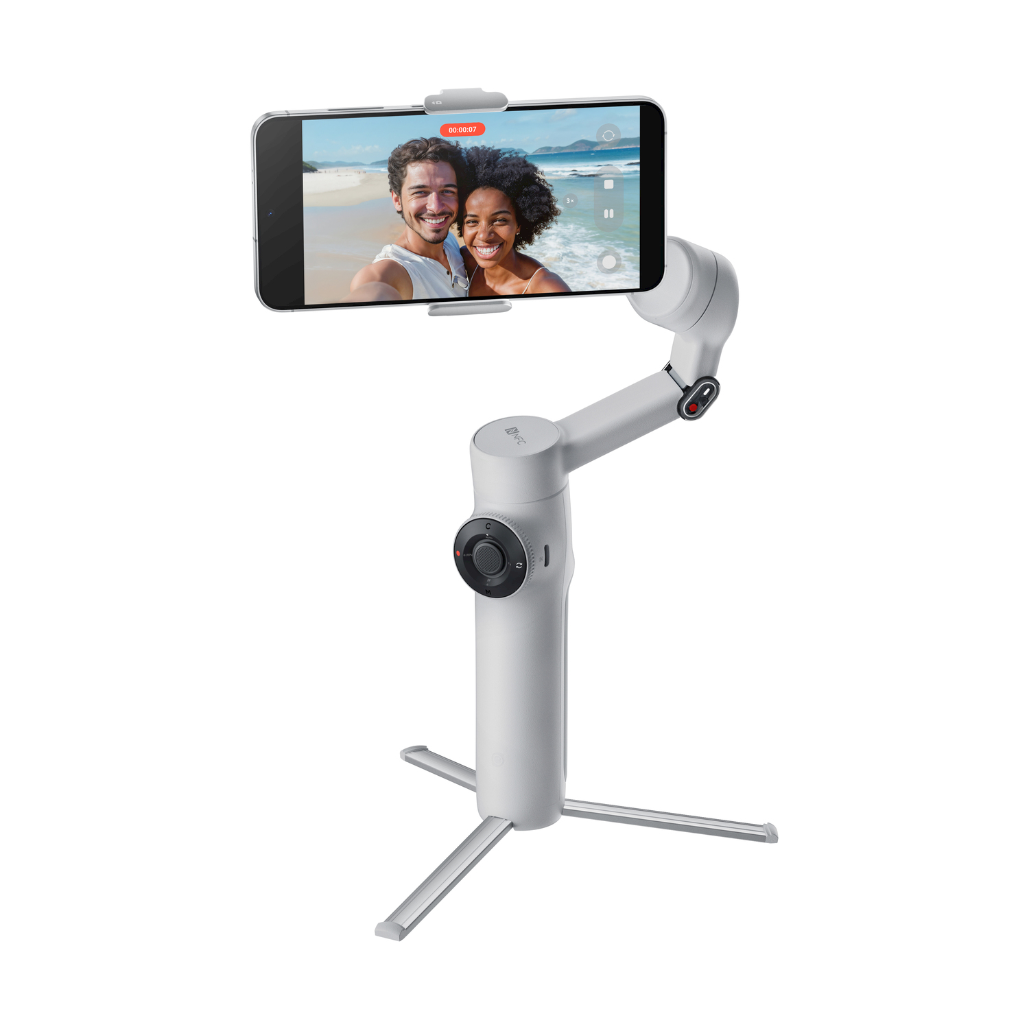 Uno stabilizzatore per telefono bianco tiene uno smartphone che mostra una coppia sorridente sulla spiaggia. Lo stabilizzatore ha una base a treppiede.