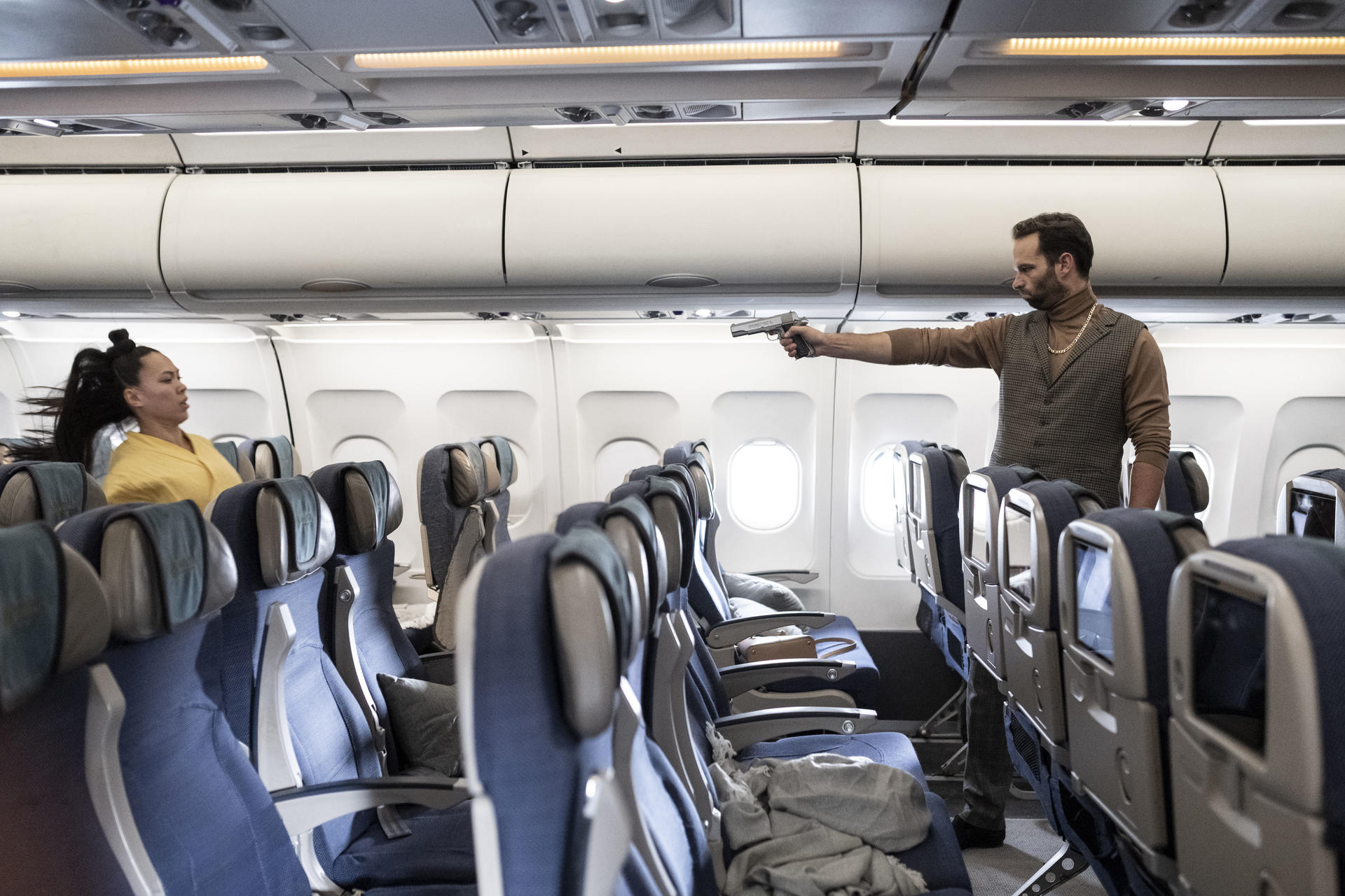 Ein Mann mit einer Pistole zielt auf eine Frau in einem Flugzeug.