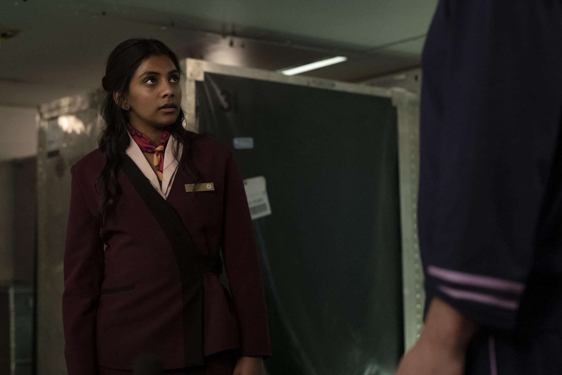 Eine Frau in Uniform mit Schal steht vor einer großen dunklen Fläche.