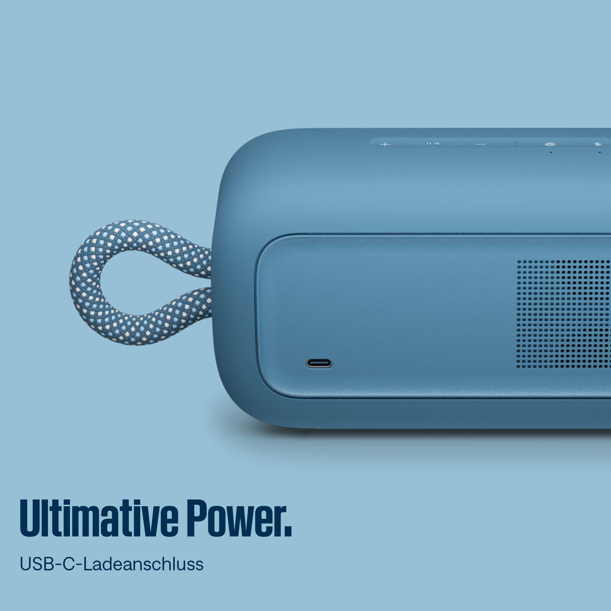 Blauer Lautsprecher mit gemustertem Griff. Text lautet 'Ultimative Power'. USB-C-Ladeanschluss sichtbar.