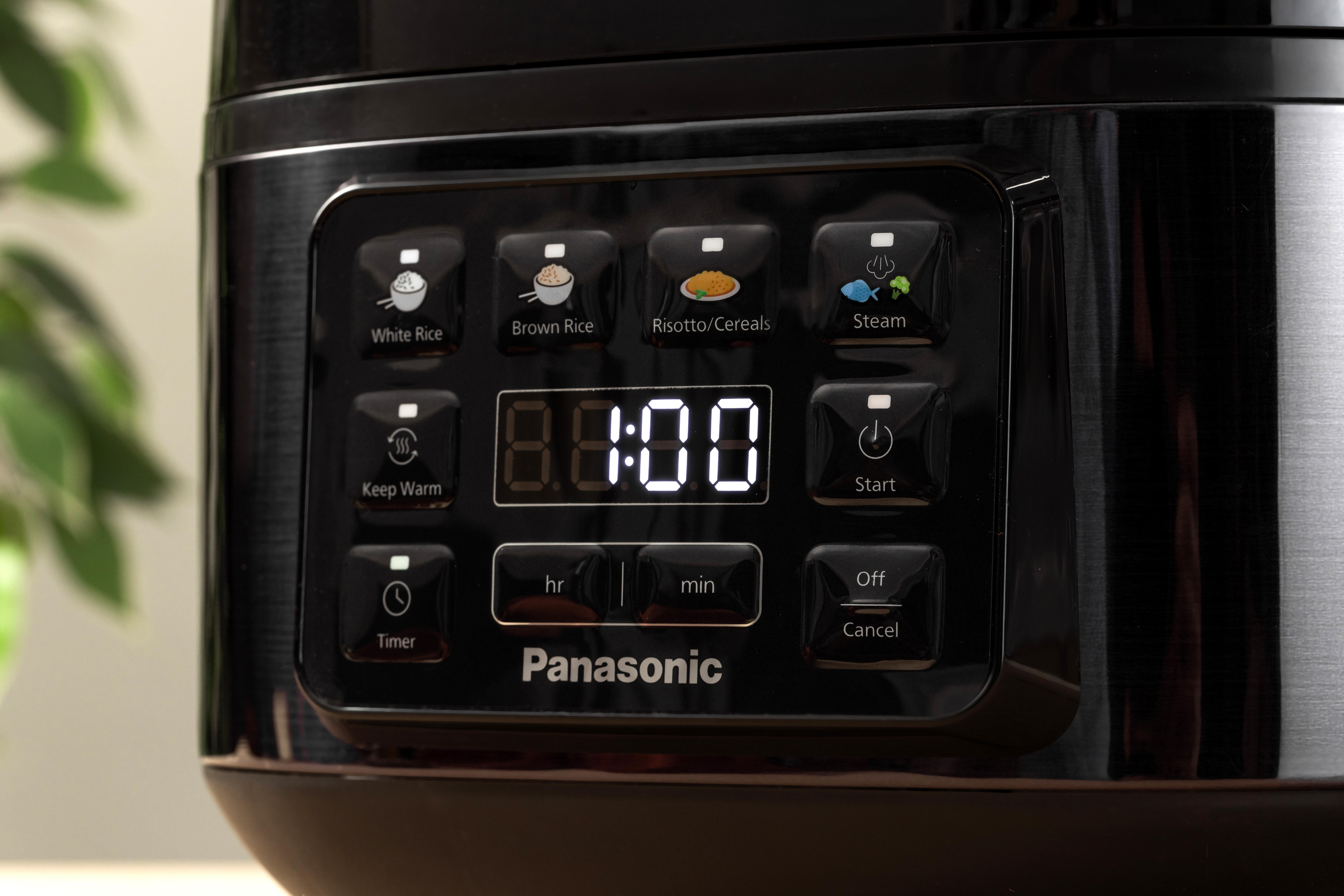 Ein schwarzer Panasonic Reiskocher mit verschiedenen Funktionstasten wie weißer Reis, Dampf und Timer, die Anzeige zeigt 8:00.