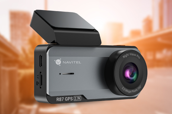 Egy Navitel R87 GPS 2.7K fedélzeti kamera látható. Szürke és fekete, elöl lencsével és napellenzővel. A háttér elmosódott.