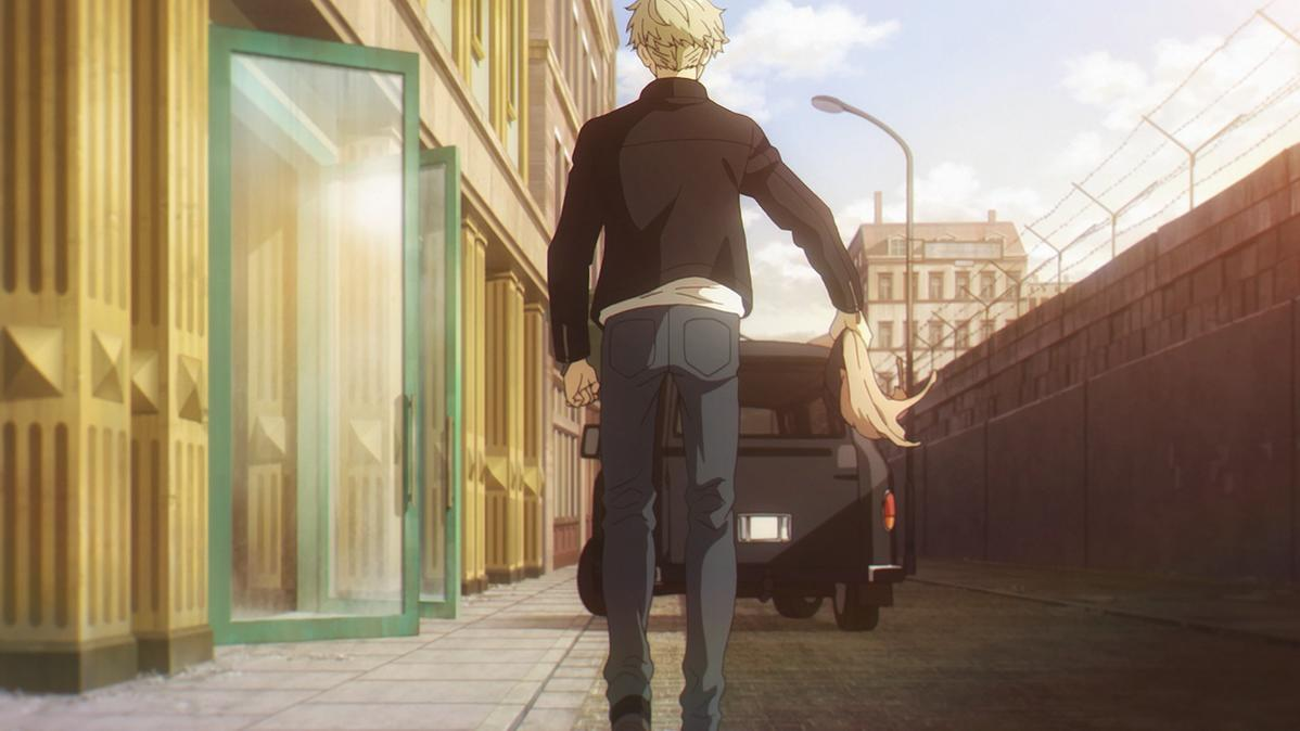 Ein Mann in schwarzer Jacke und Jeans geht vom Betrachter weg. Er hält blonde Haare. Gebäude und ein schwarzes Auto sind im Hintergrund.