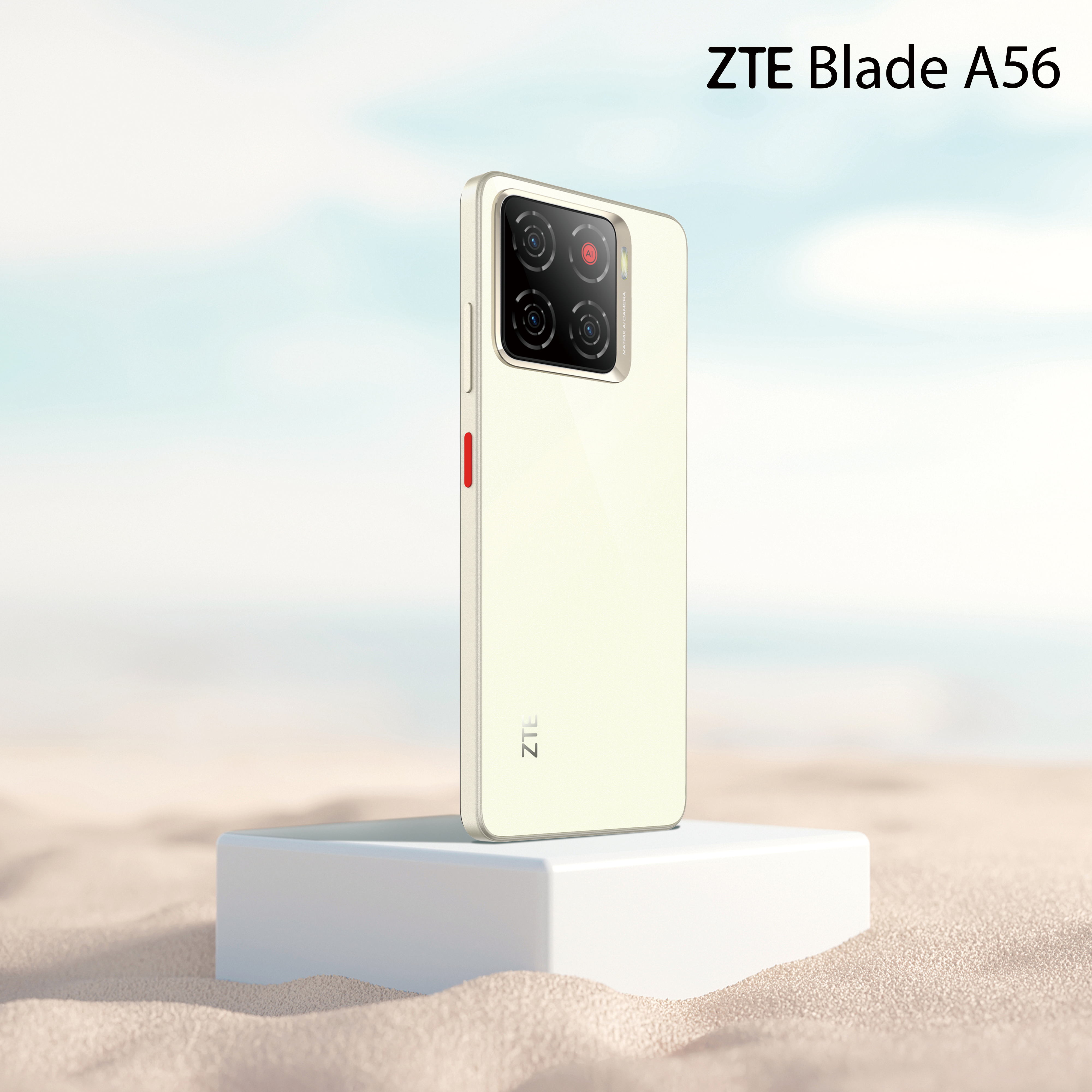 ZTE Blade A56 Telefon auf einem weißen Block, auf sandartiger Oberfläche. Telefon ist cremefarben mit schwarzer Kamera und roter Taste.
