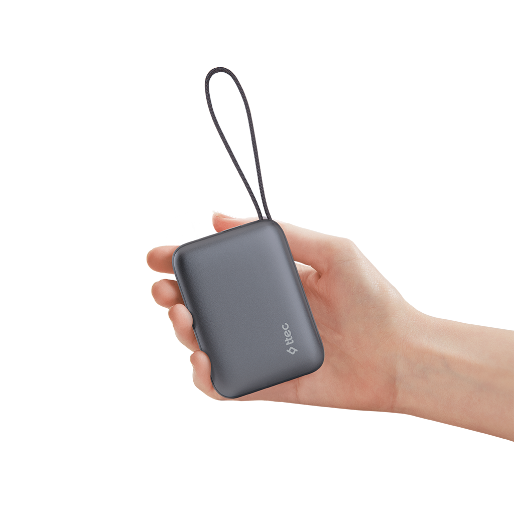 Bir el, halkalı gri bir powerbank tutuyor. Powerbank'te 'ttec' logosu var. Arka plan beyaz.