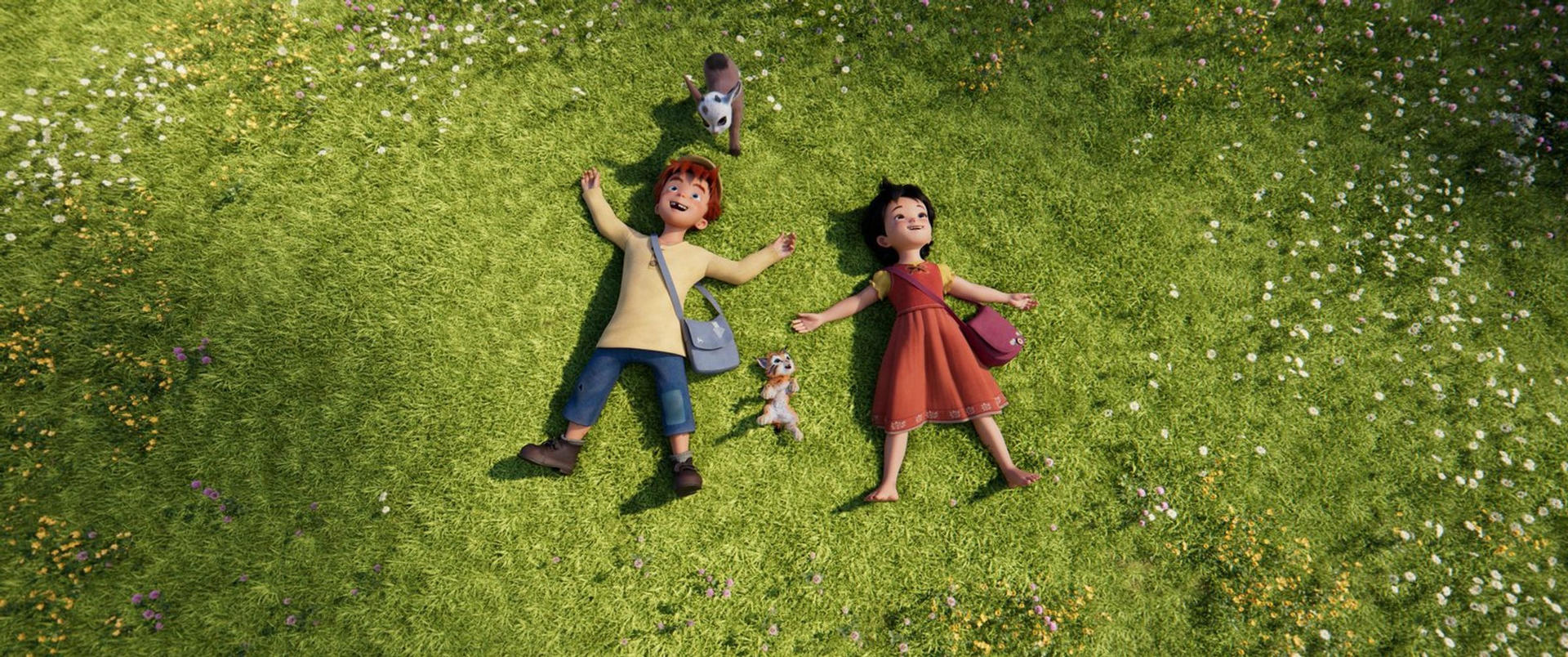 Zwei Kinder liegen auf grünem Gras, Arme ausgestreckt, mit einem Spielzeughund und einer Ziege. Das Gras ist mit Blumen übersät.