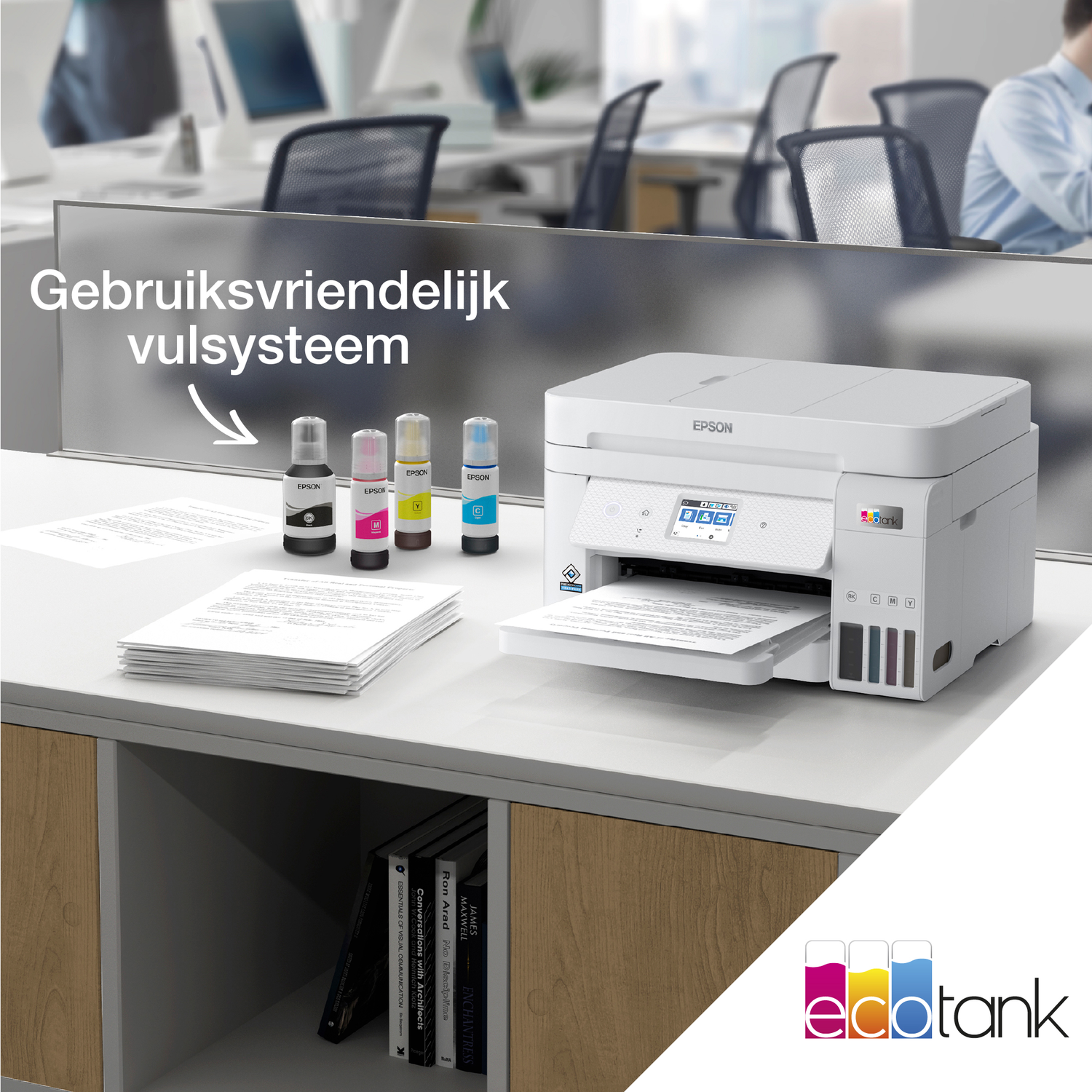 White Epson printer on a desk with ink bottles. Documents and books are also present. Background features office setting and chairs.