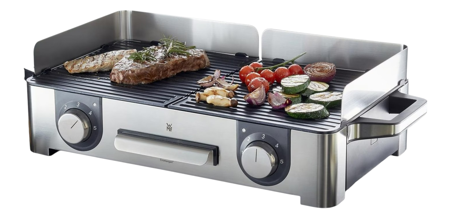 Ein Edelstahlgrill mit Steak, Gemüse und Tomaten. Es hat Drehregler und einen Griff. Gemüse umfasst Zucchini und Zwiebeln.