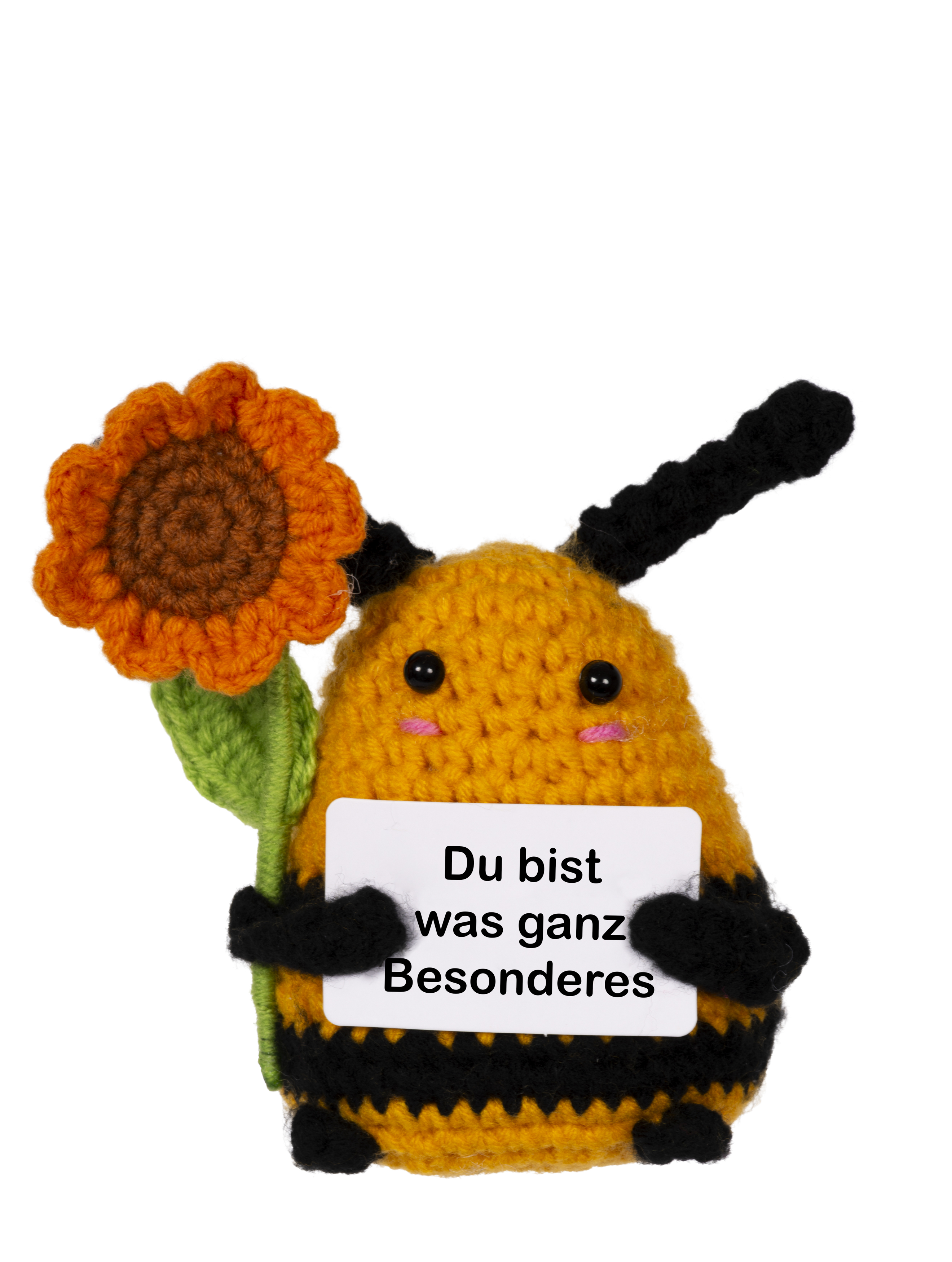 Eine gestrickte Biene hält eine Sonnenblume. Sie zeigt ein Schild mit deutschem Text.