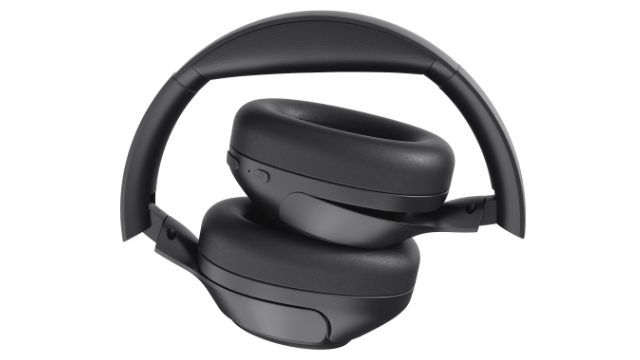 Czarne słuchawki, złożone. Nauszniki są ułożone jeden na drugim. Pałąk nagłowny wygina się ku górze. Tło jest białe.