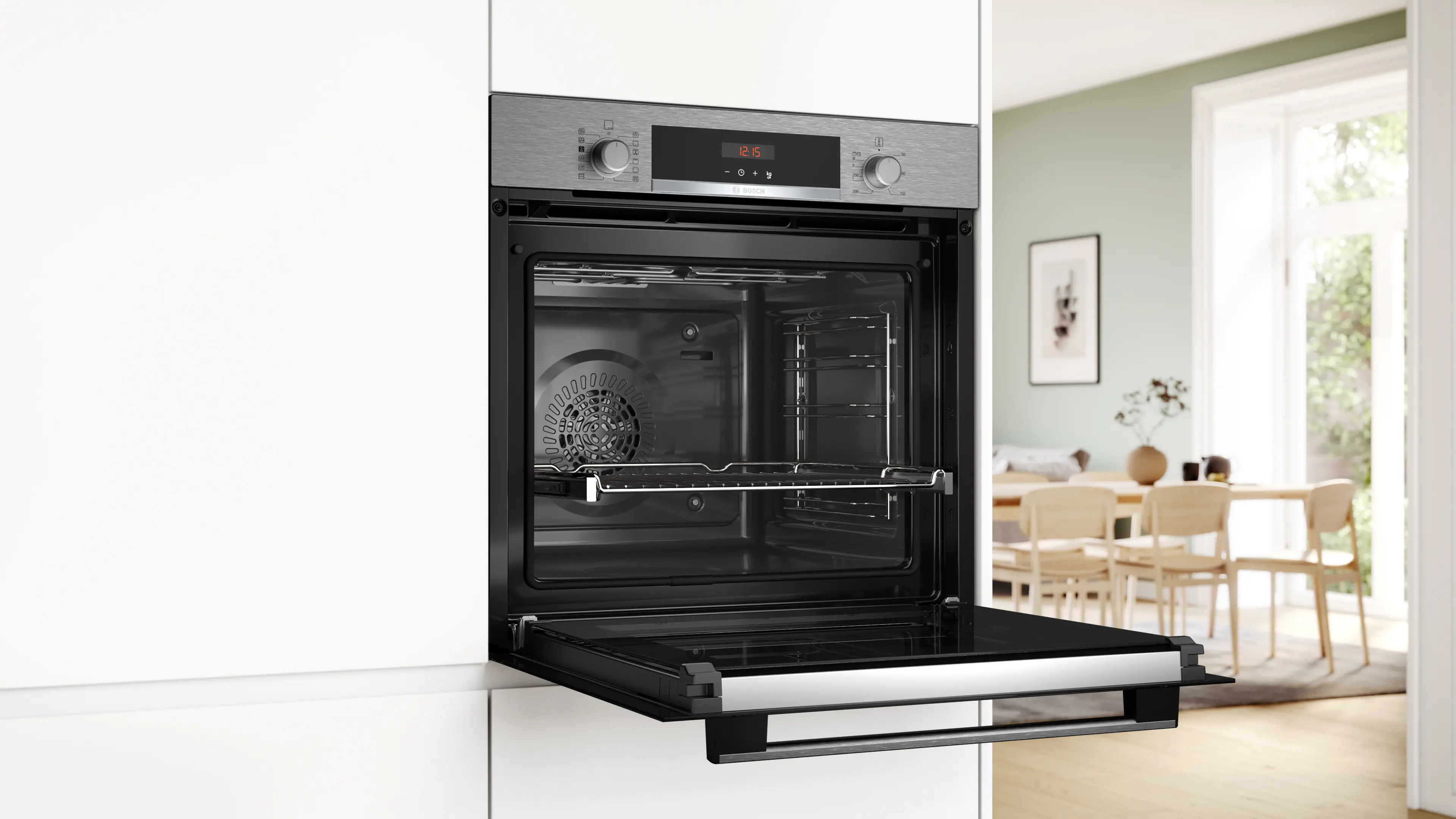Horno abierto con rejillas interiores. La puerta del horno está abajo. Arriba hay un reloj digital. Una cocina en el fondo.