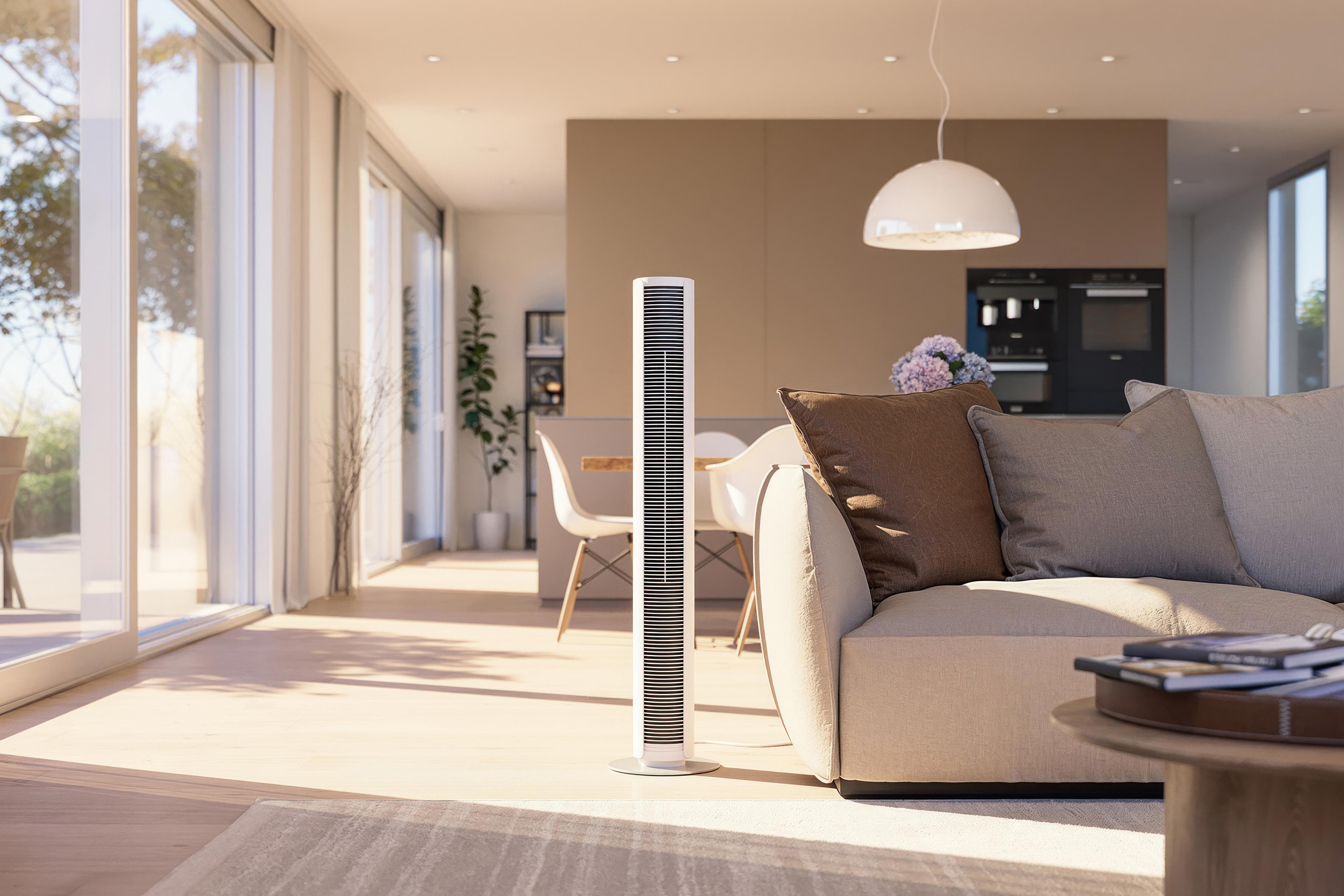 Ein modernes Wohnzimmer mit weißem Ventilator, Sofa und Couchtisch. Fenster und Essbereich im Hintergrund.