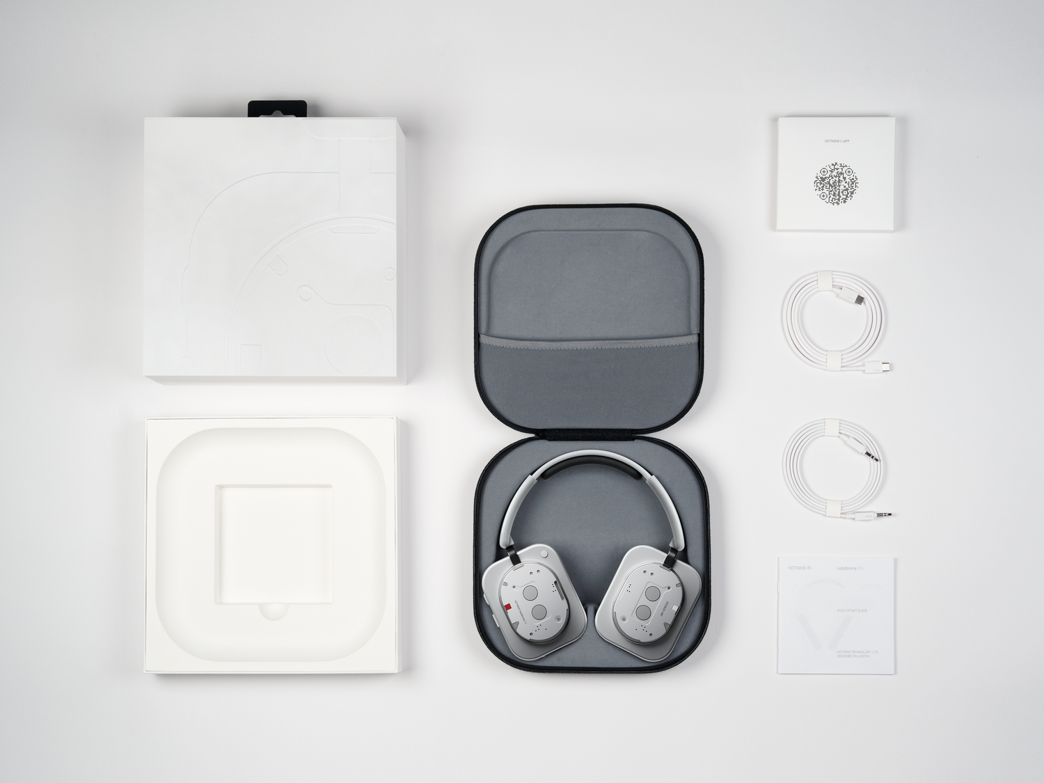 Auriculares blancos, estuche y accesorios sobre fondo blanco. Incluye cables, instrucciones y cajas. Auriculares grises dentro del estuche.