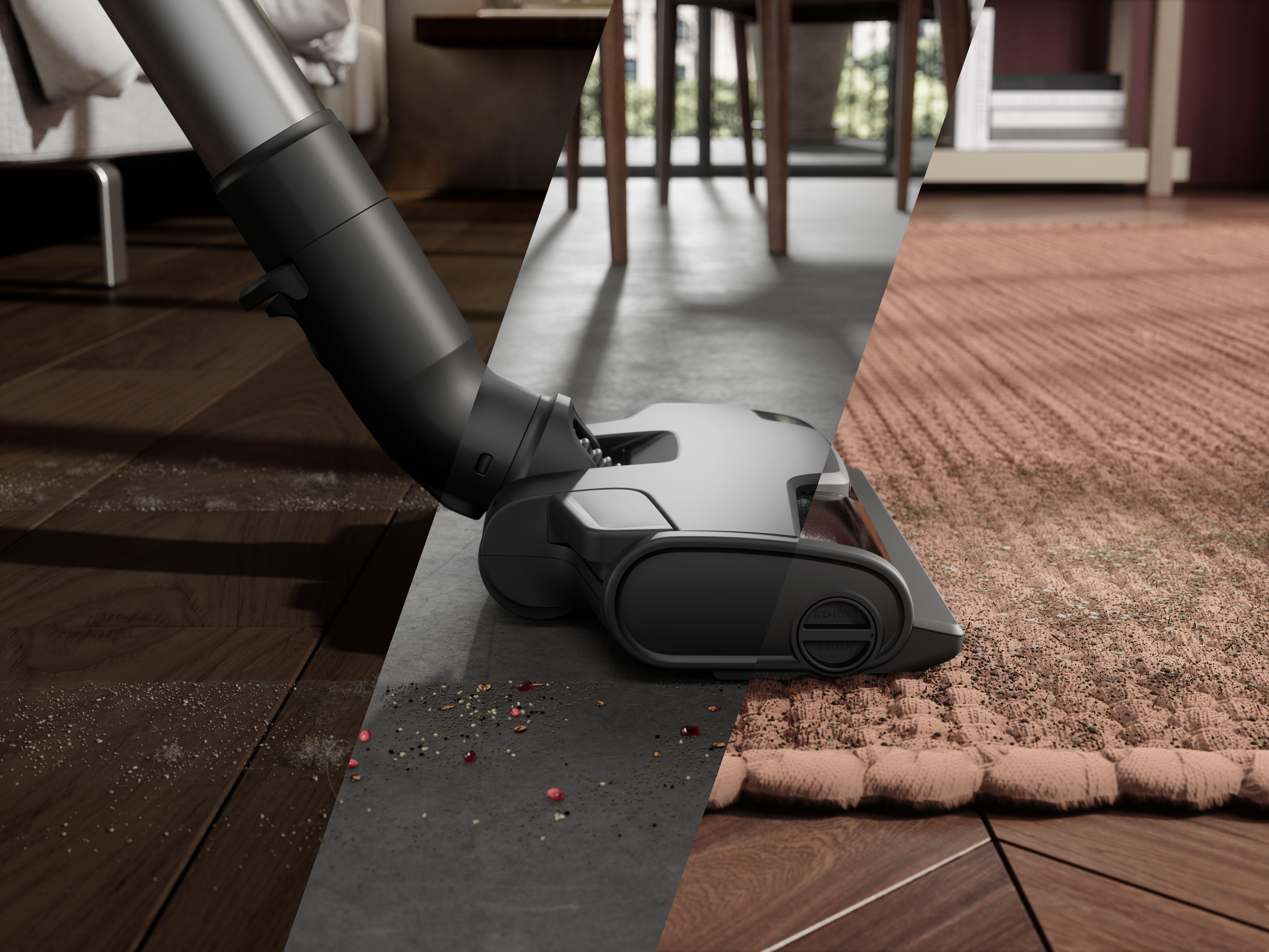 Ein Staubsauger reinigt einen Raum mit Holz-, Beton- und Teppichboden. Trümmer sind sichtbar.