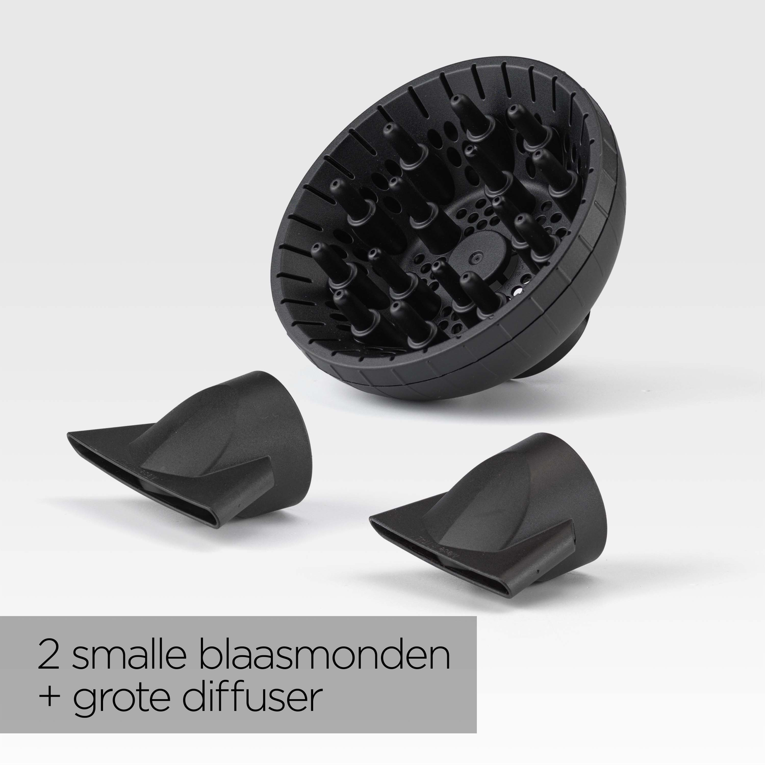 Zwarte haardroger opzetstukken: een grote diffuser en twee kleinere nozzles, alles op een witte achtergrond.