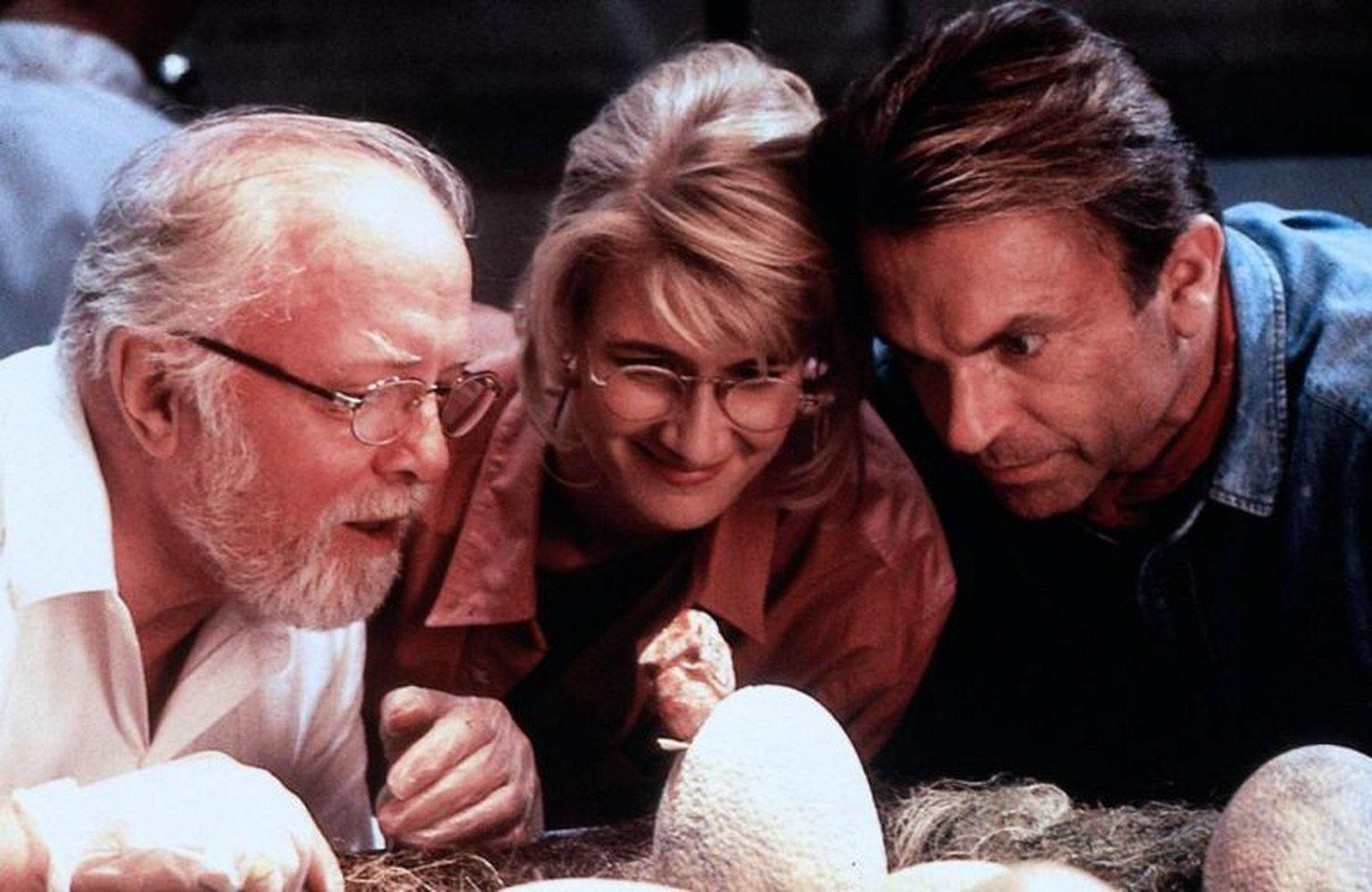 Drei Personen betrachten Dinosaurier-Eier. Ein Mann mit Brille und Bart. Eine Frau mit Brille und ein Mann schauen intensiv.