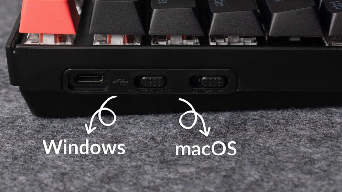 Nahaufnahme der Unterseite einer schwarzen Tastatur. Es gibt zwei Schalter mit der Aufschrift "Windows" und "macOS". Ein USB-C-Anschluss ist sichtbar.