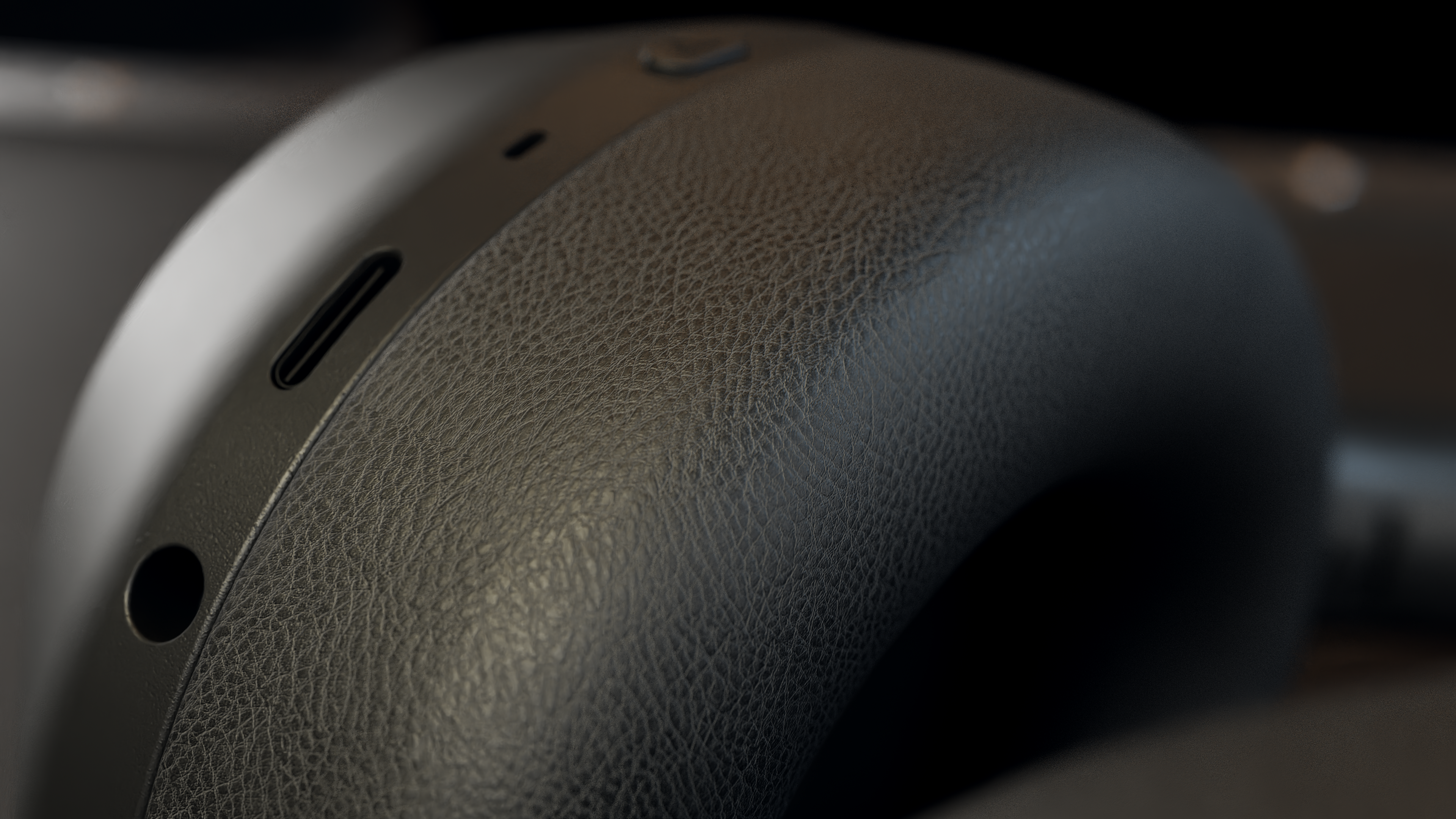 Zbliżenie czarnej słuchawki. Ma teksturowaną skórzaną powierzchnię z portem i przyciskiem. Tło jest rozmyte.